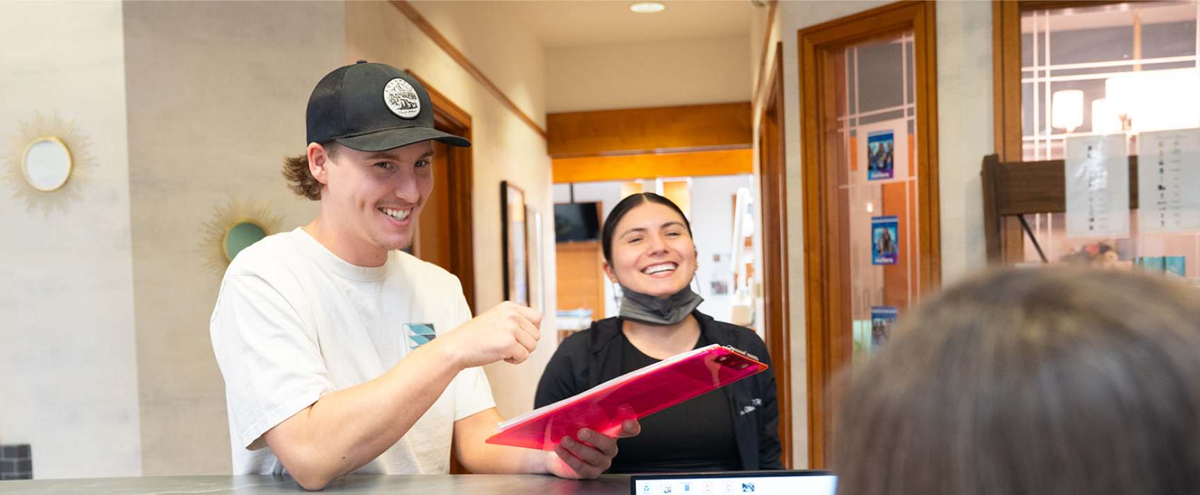 A Patient At High Desert Dental At The Front Desk Smiling With A Nurse