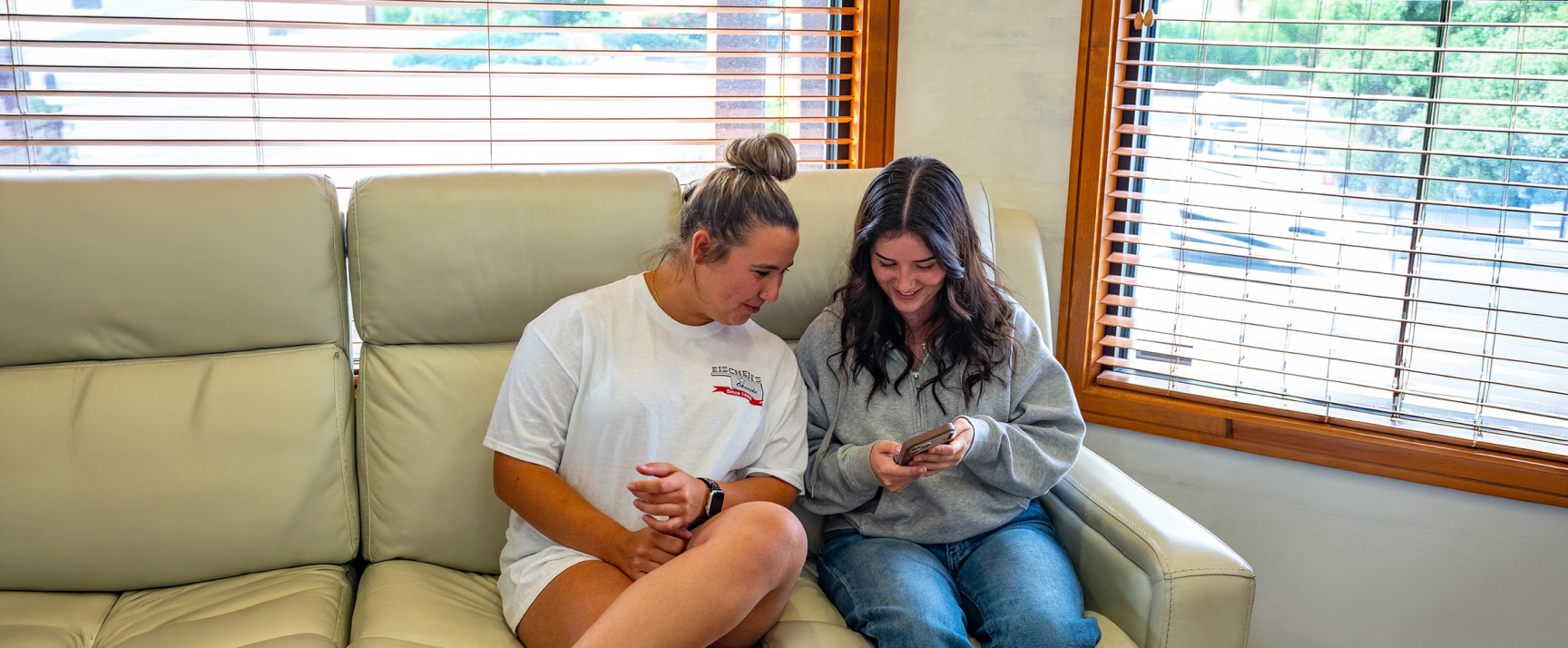 Two Patients In The Lobby Of High Desert Dental Looking At A Phone While Having Fun On A Sofa